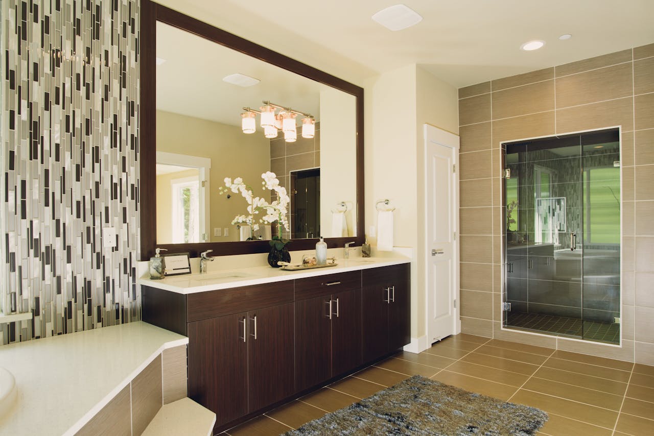 Home Elegant bathroom featuring modern sink and shower with decorative tiling and large mirror.