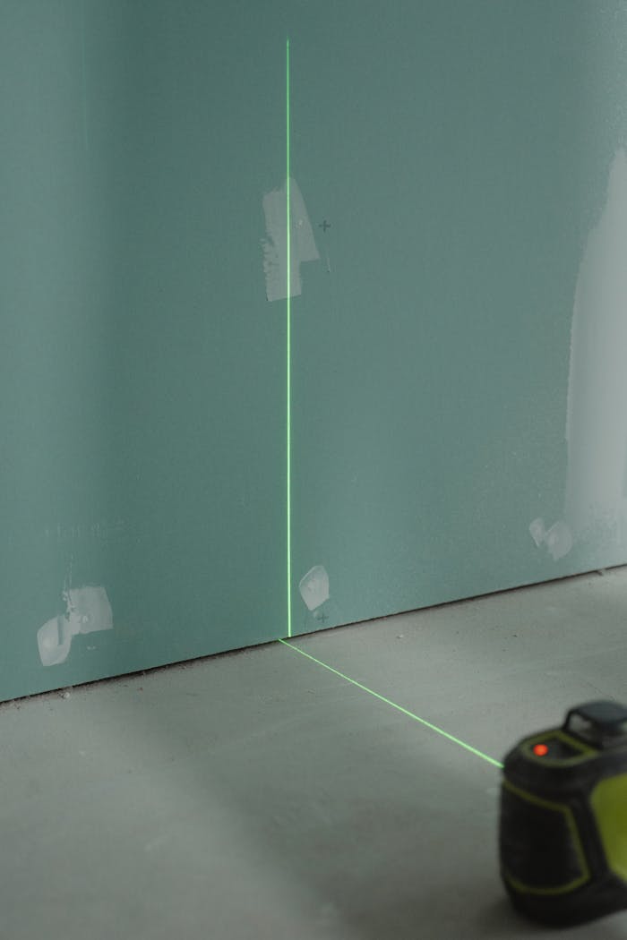 Laser alignment tool projecting light on a wall for precise measurement in construction.